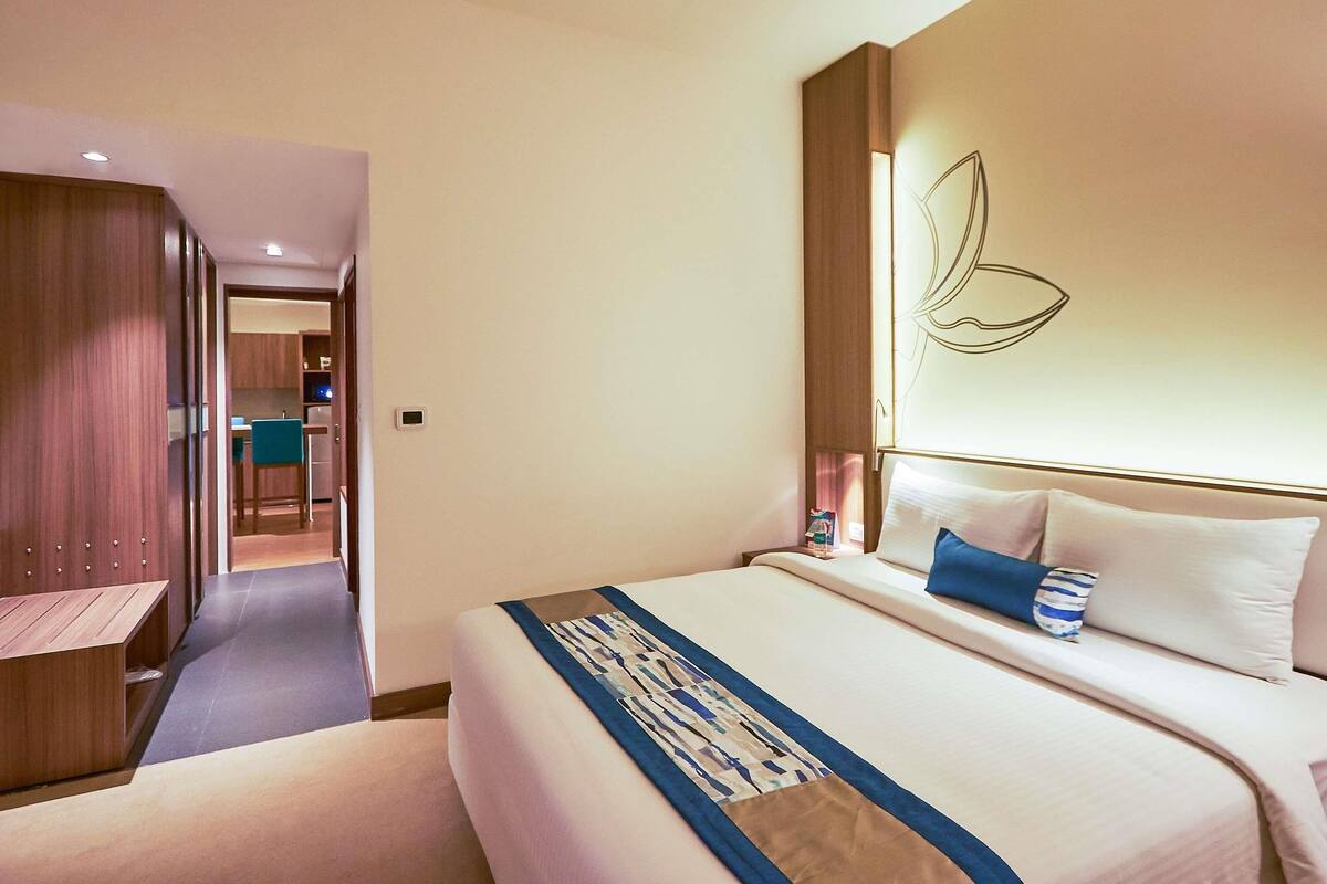 A hotel room with a bed, bedside table, and a desk with a chair.