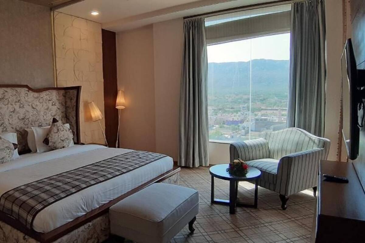 Een hotelkamer met een groot bed, een stoel, een tafeltje en een televisie.