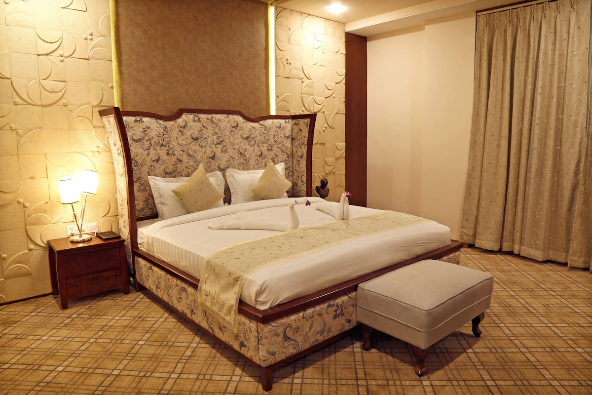 Een hotelkamer met een groot bed, een nachtkastje, een lamp en een decoratief hoofdbord.