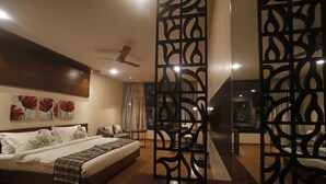 Un dormitorio con una cama grande, un ventilador de techo y un separador decorativo.