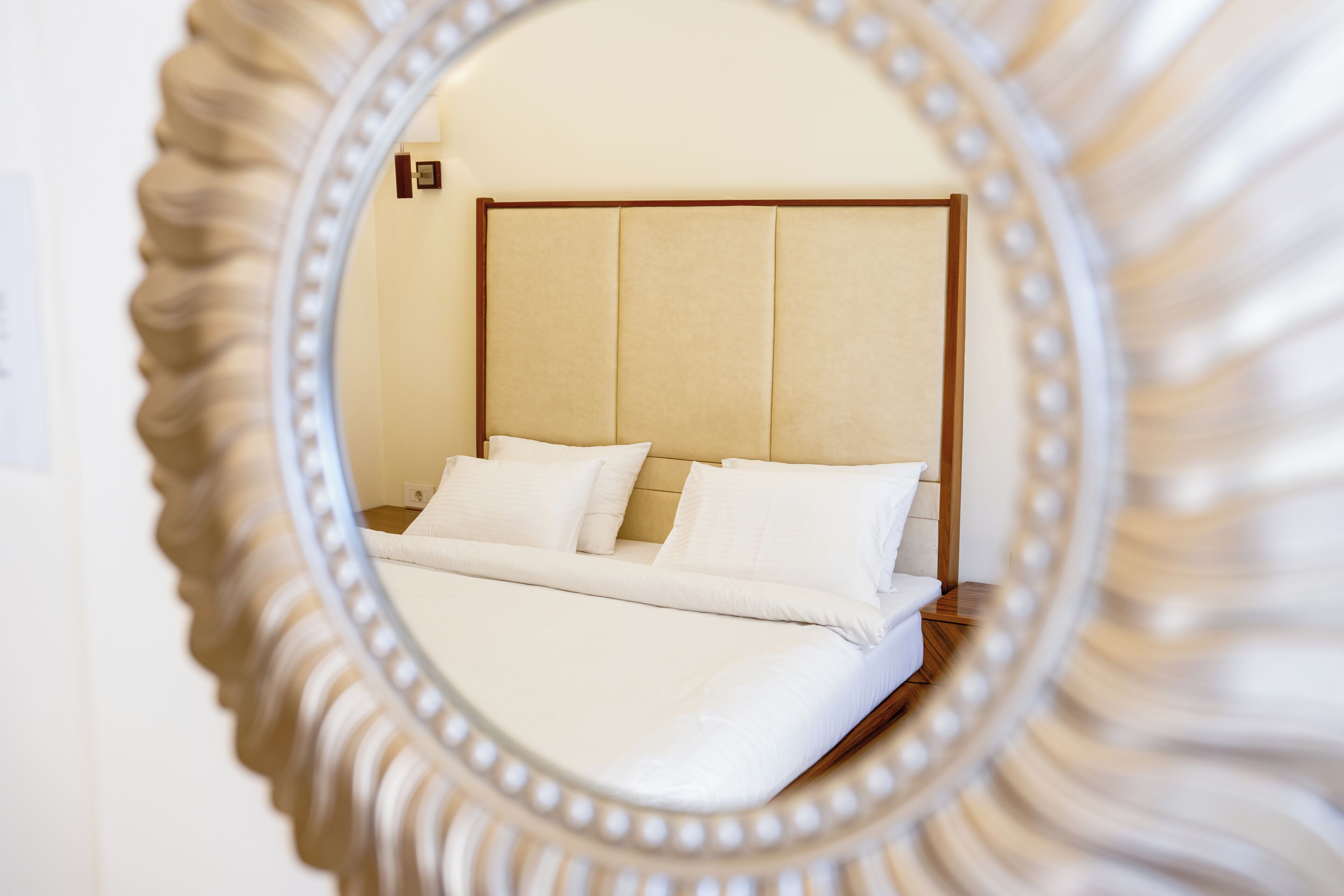 A bed with white linens and a wooden headboard in a hotel room.