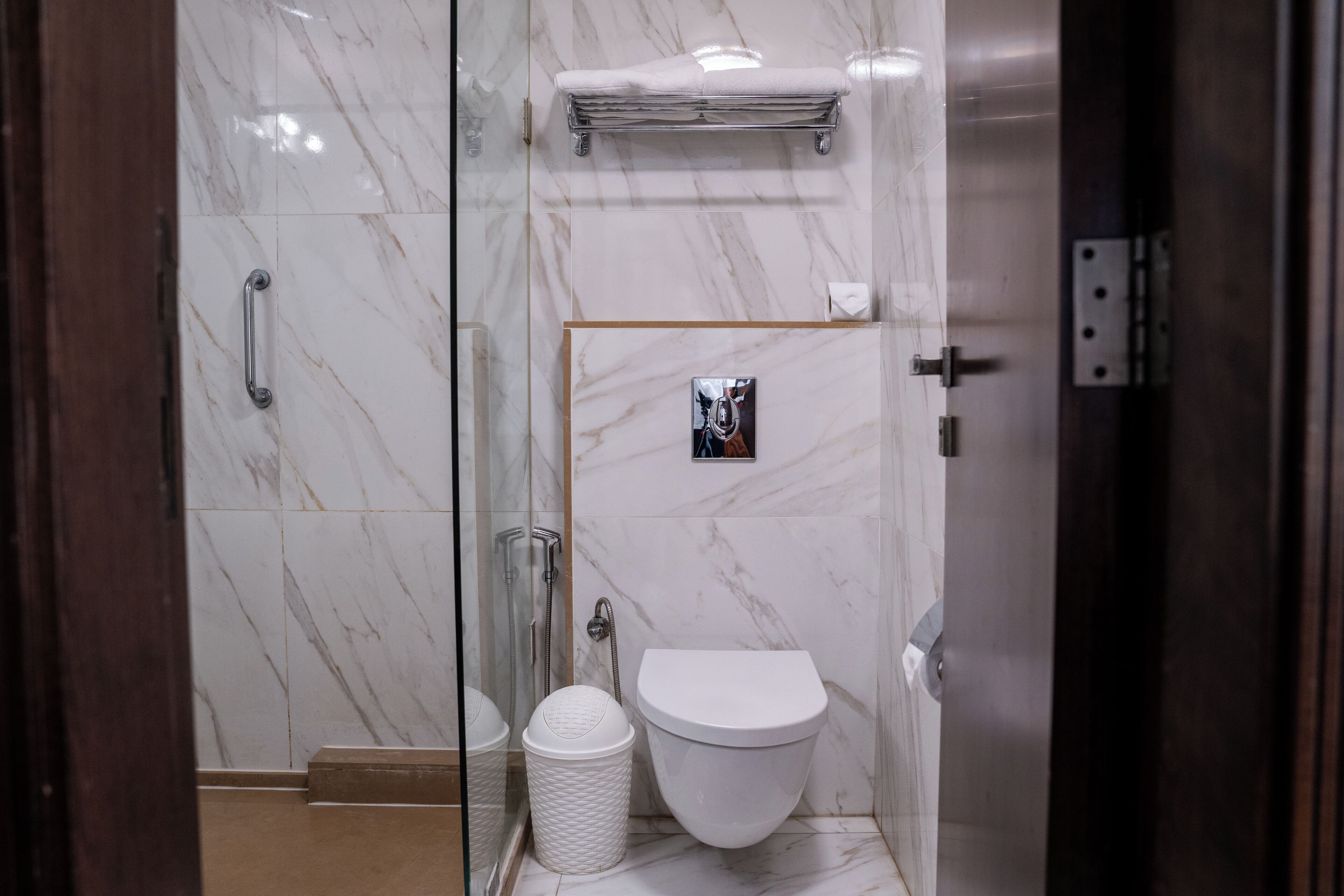 Un baño con cabina de ducha de vidrio, inodoro blanco y perchero para toallas.