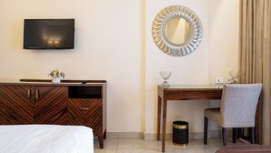 A hotel room with a bed, a wooden desk, a television, a mirror, and a chair. - Grand Concerto Hotel (Beirut)