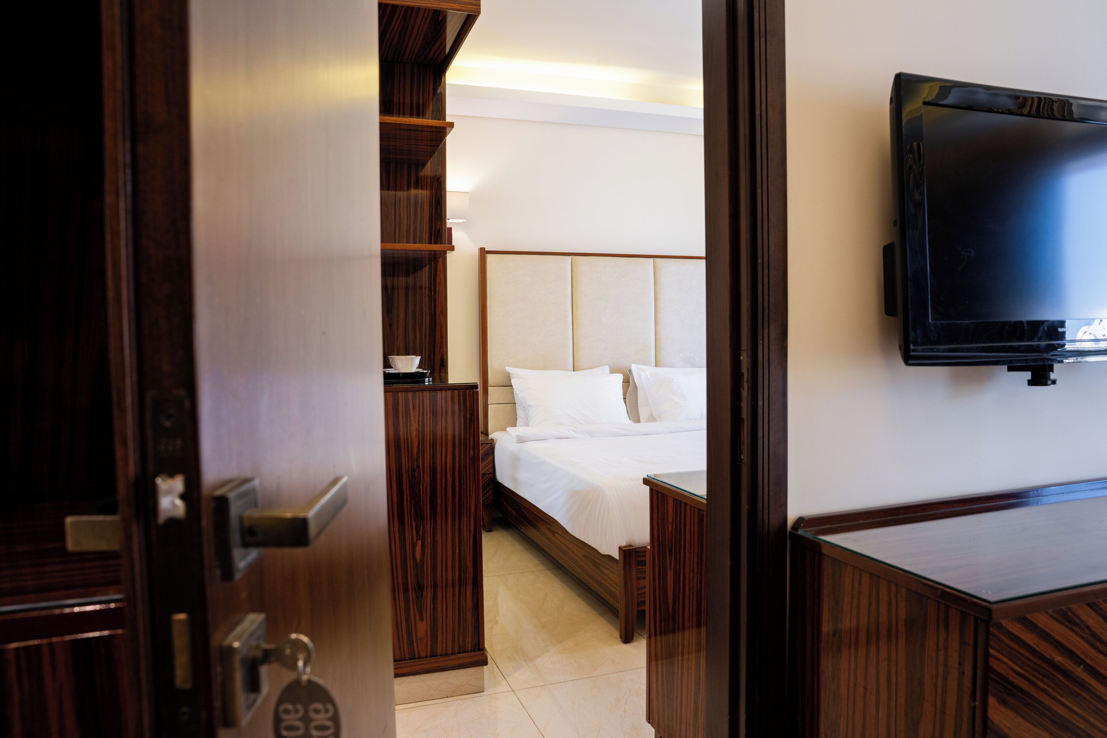 Una habitación de hotel con cama, mesita de noche y televisor en la pared.