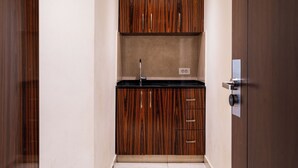 A compact kitchen with wooden cabinets, a black countertop, and a built-in sink. - Grand Concerto Hotel (Beirut)
