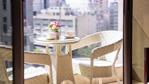 A balcony with wicker chairs, a small round table, and a vase of flowers. - Grand Concerto Hotel (Beirut)