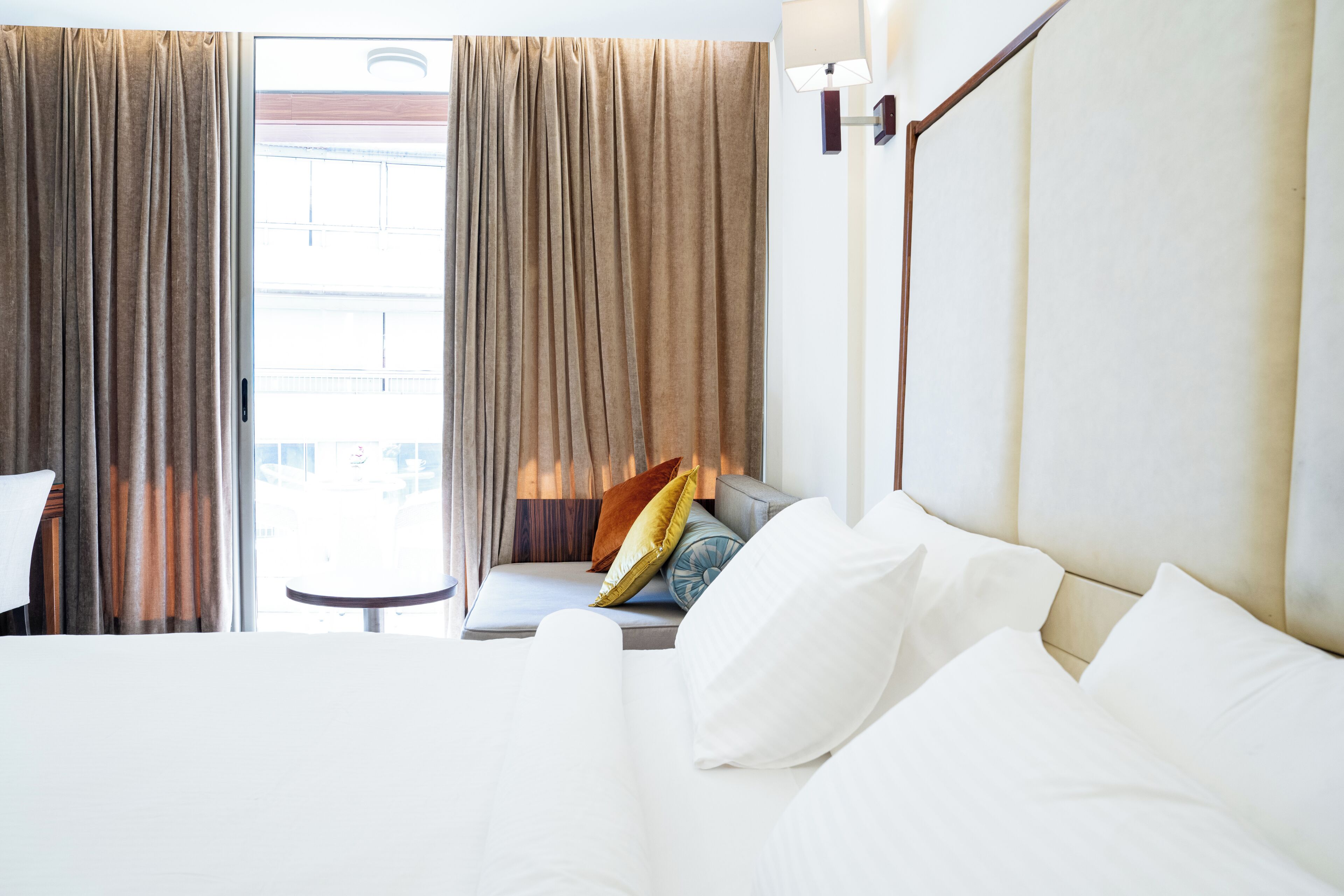 A hotel room with a bed, a sofa, a small table, and curtains.
