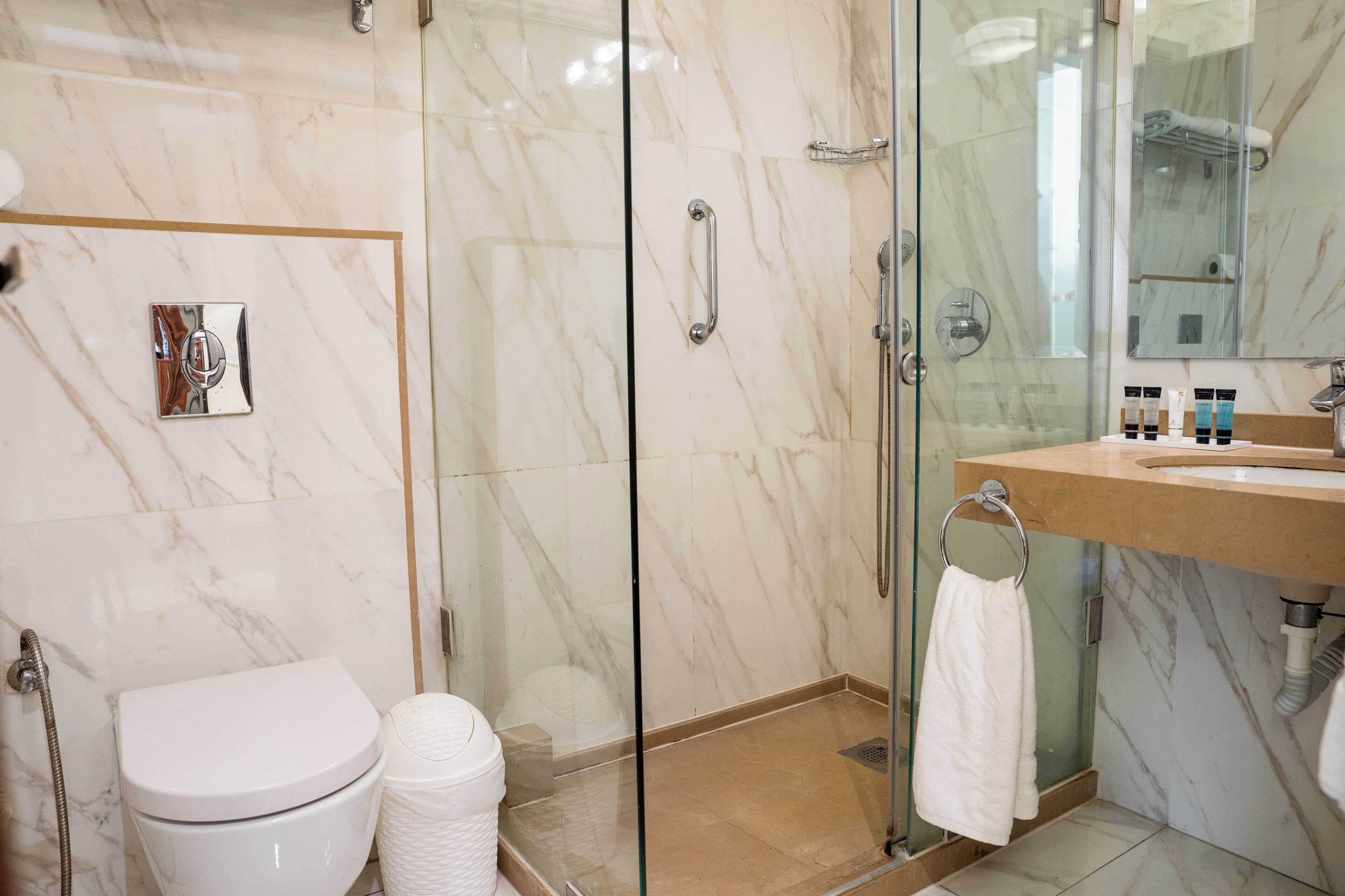 A modern bathroom with a glass shower enclosure, a toilet, and a vanity with toiletries.