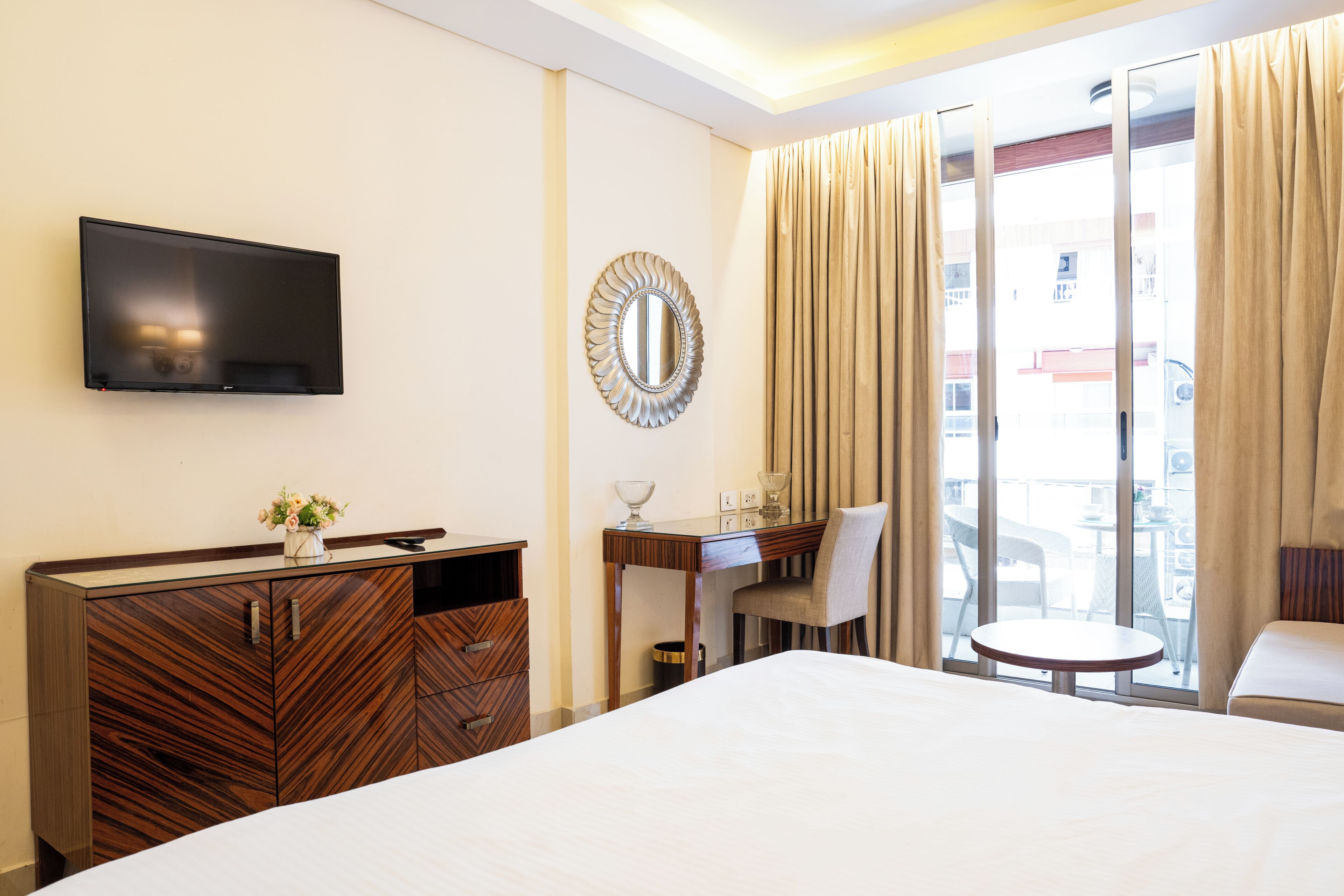 A hotel room with a bed, a desk, a chair, a television, and a large window with curtains.
