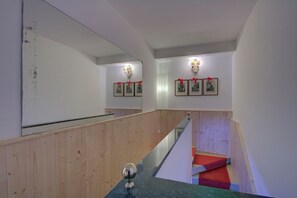 A staircase with wooden railings and a red carpet. There are wall-mounted lights and framed pictures with red ribbons. - ZANIPOLO Marco-canal (Venice)
