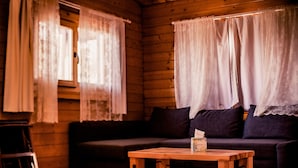 Interior acogedor de una cabaña con suelo de madera, un sofá oscuro y una pequeña mesa de madera.