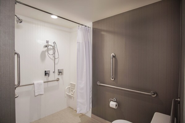 Un baño moderno con ducha, inodoro y barras de apoyo.