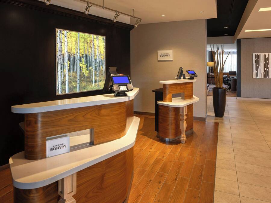 Een receptiebalie met een digitaal scherm, een bord met daarop 'Marriott Bonvoy' en een groot schilderij met een boslandschap.