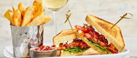 A sandwich with a side of fries and a glass of white wine on a plate.