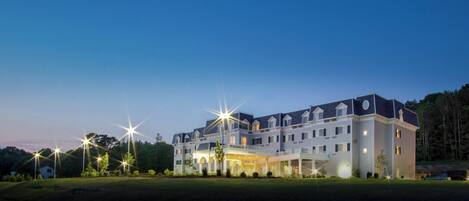 A large, multi-story hotel with a symmetrical facade, multiple balconies, and a well-lit entrance.