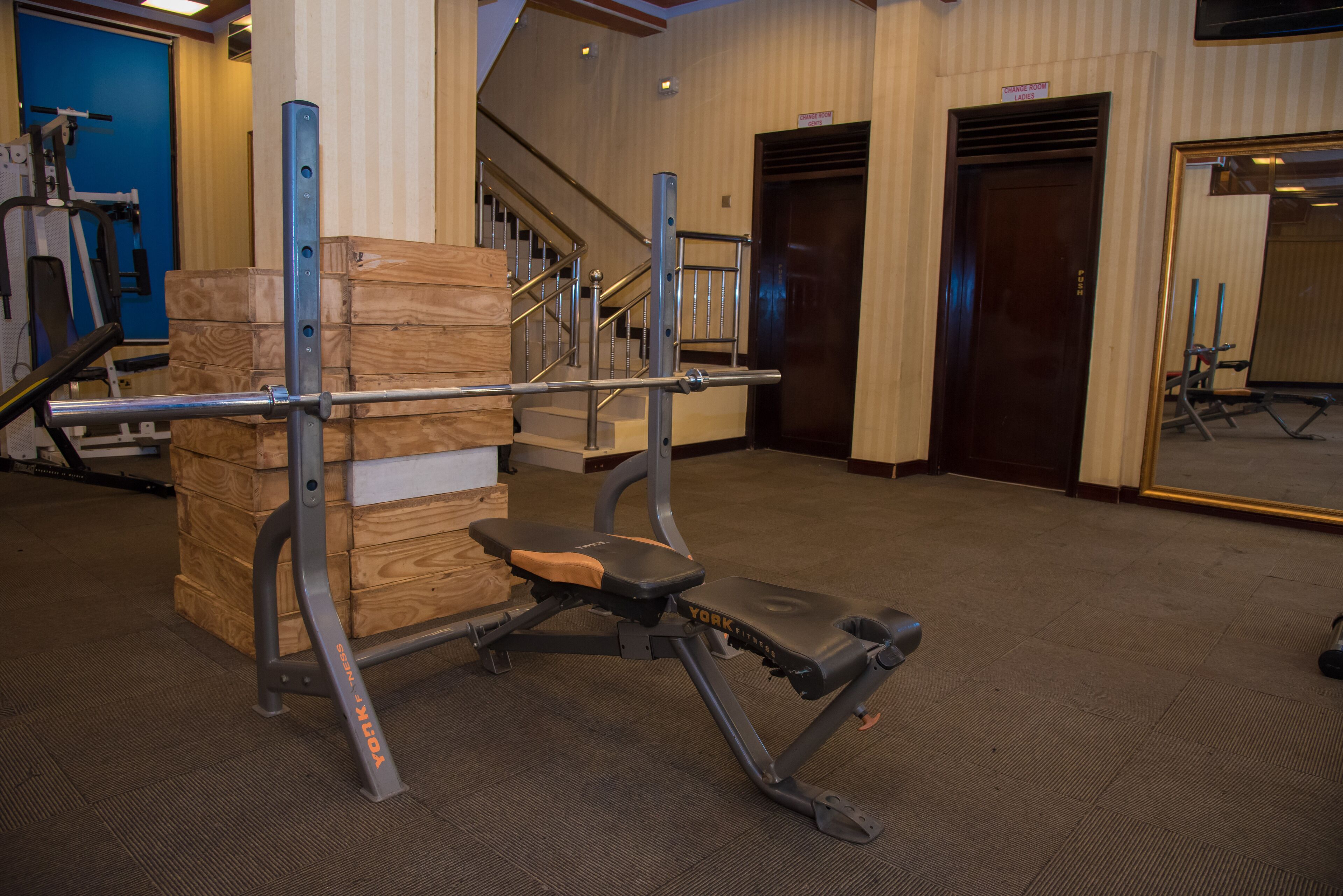 Un gimnasio con equipo de ejercicio, un banco de madera y una escalera.