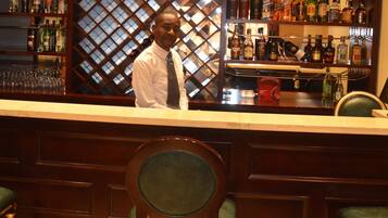 A bar area with a counter, shelves of liquor bottles, and a glass display case.