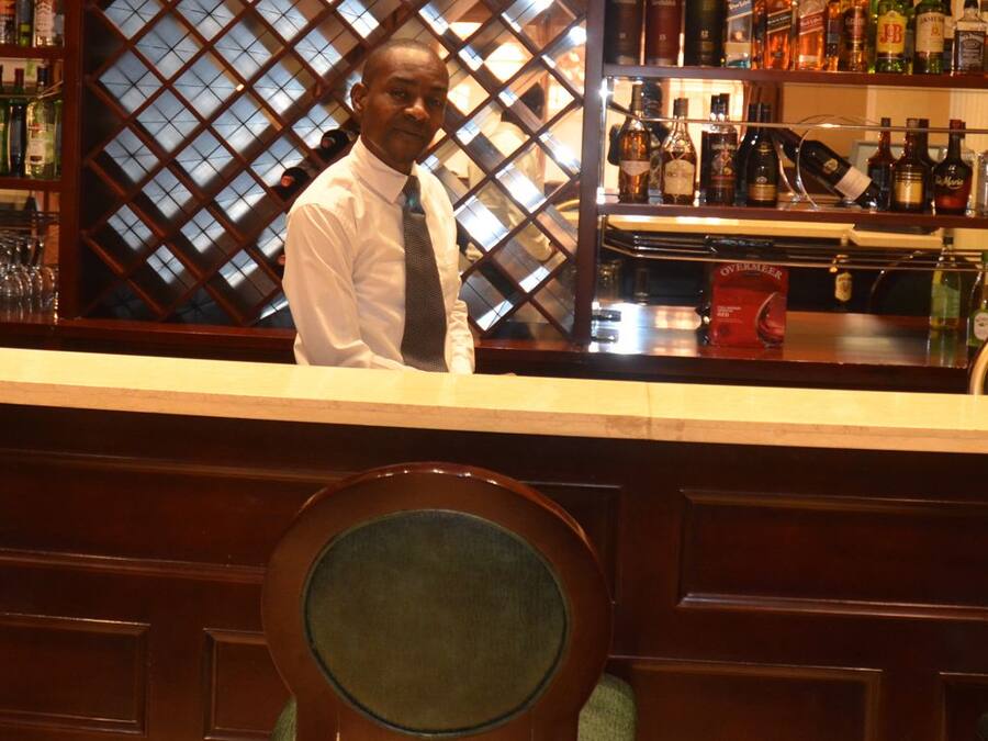 A bar area with a counter, shelves of liquor bottles, and a glass display case.