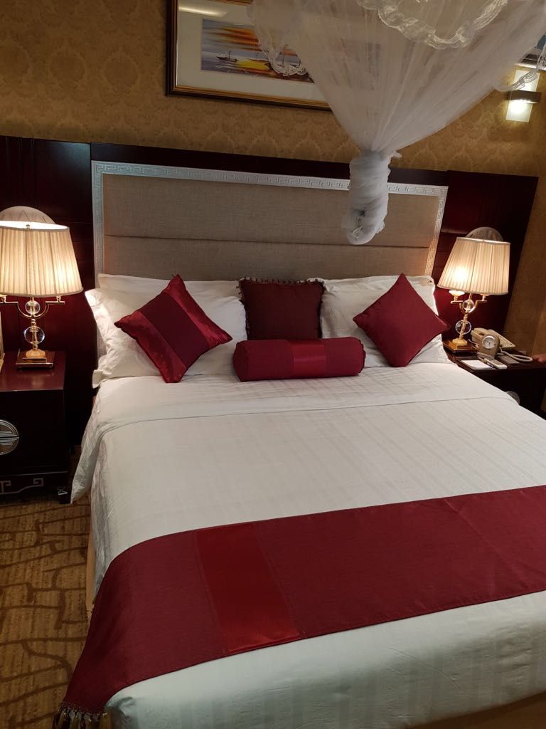 Una habitaci ón de hotel con una cama grande, dos mesitas de noche con lámparas y un dosel.