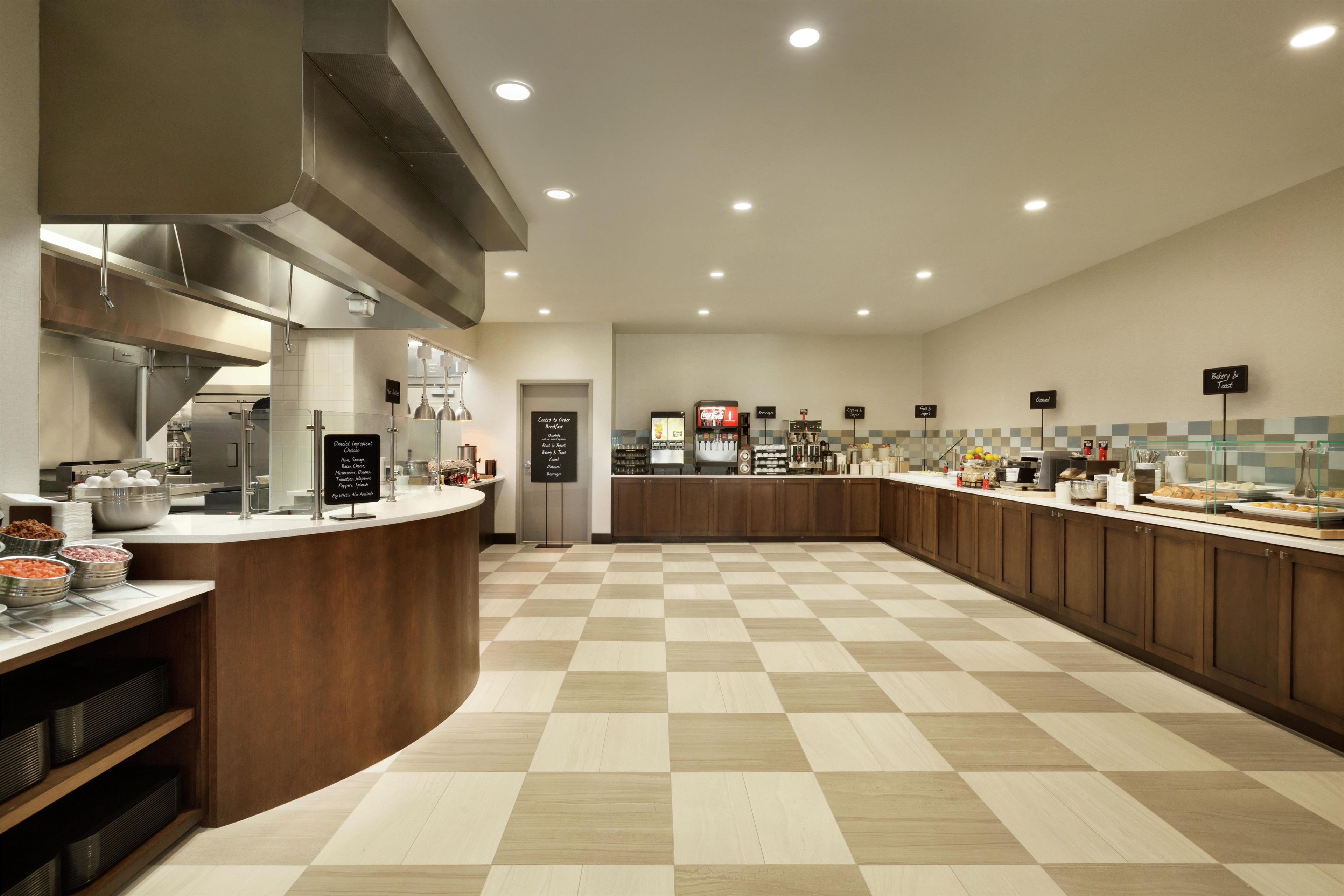 A spacious kitchen with a checkered floor, stainless steel appliances, and a variety of food stations.