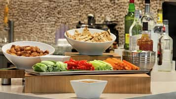 A buffet table with various food items and condiments, including bowls of nuts, vegetables, and a bowl of chips.