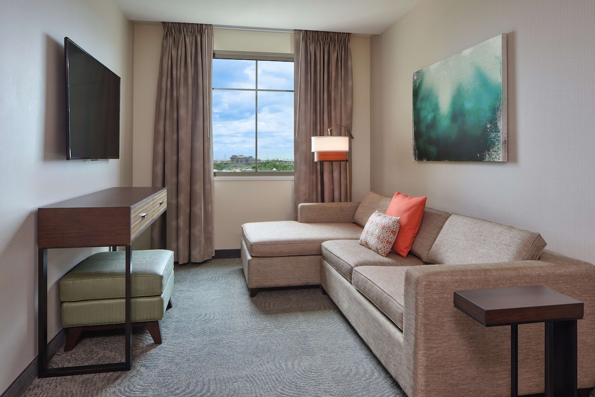 Hotelkamer met een bank, een tafeltje, een televisie, een lamp en een schilderij aan de muur.