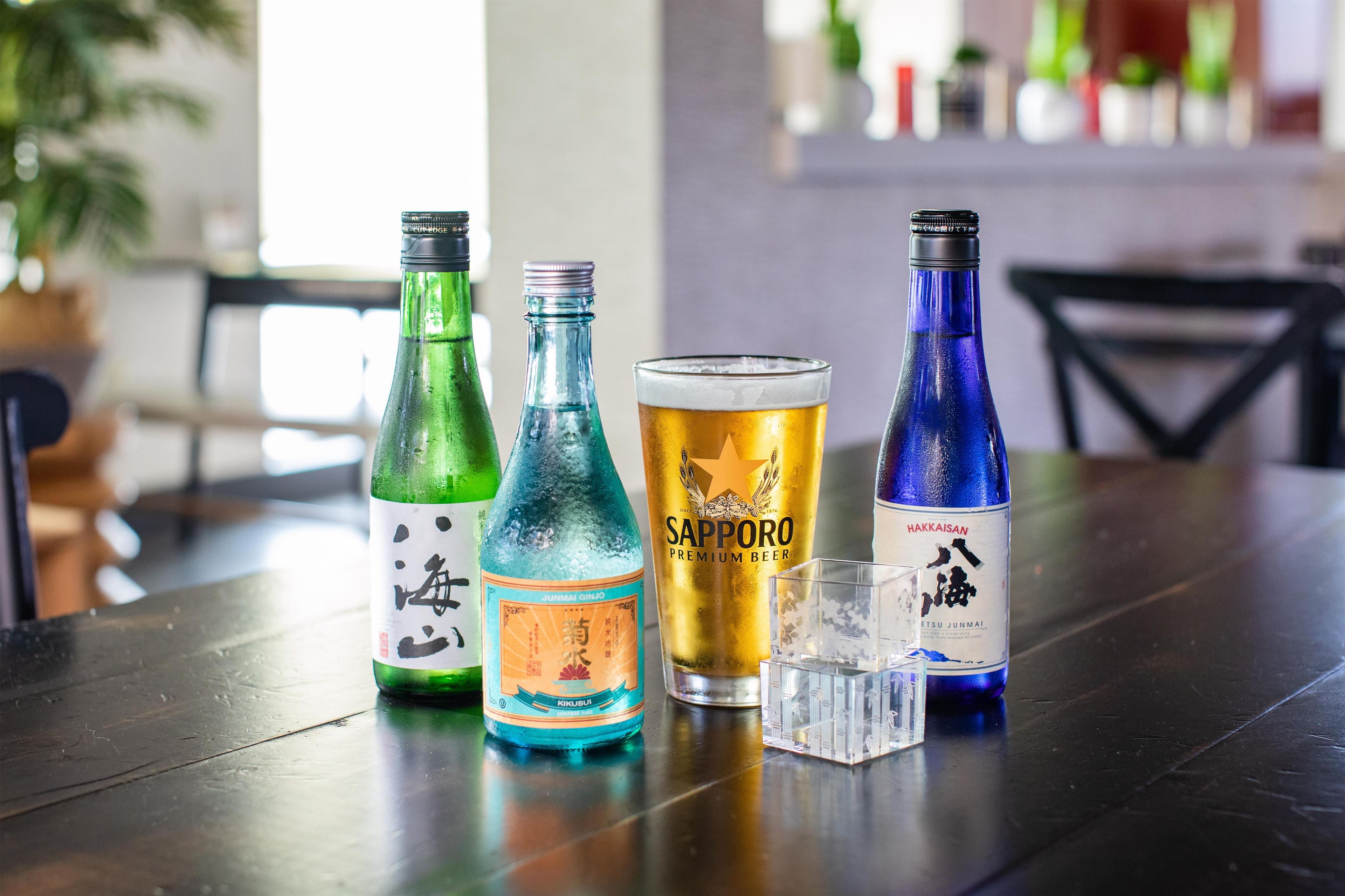 A table with various bottles and a glass of beer.