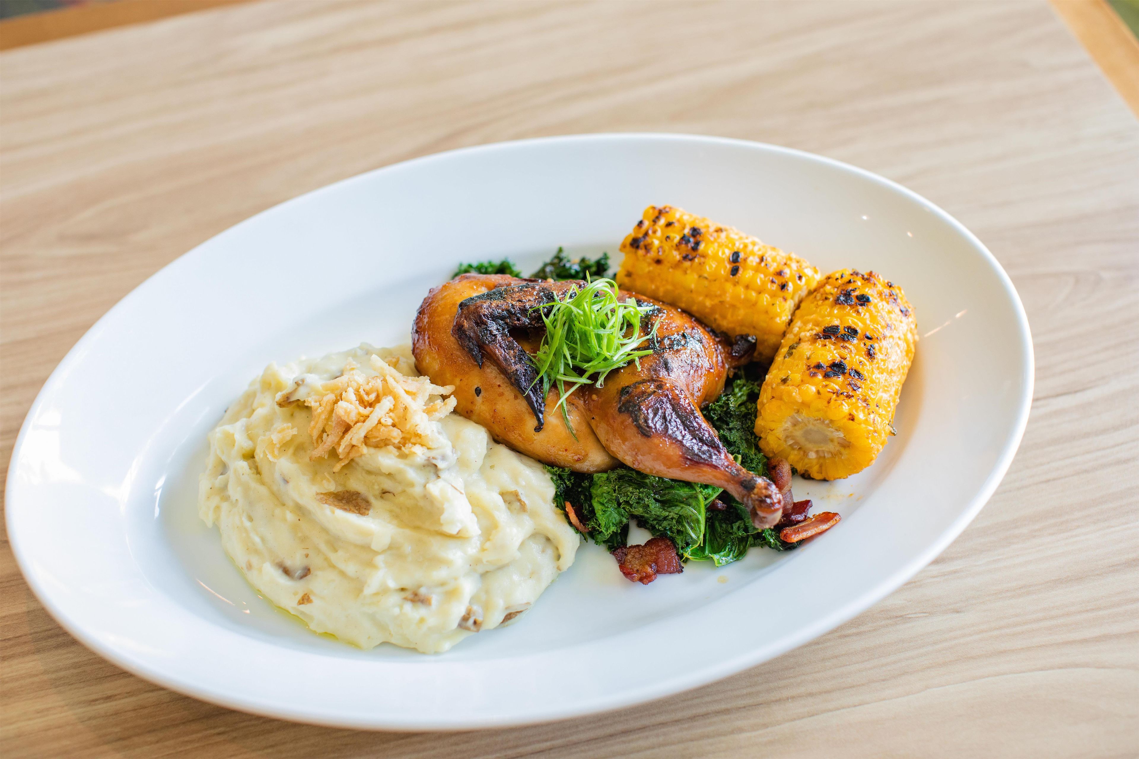 Un plato con pollo asado, elote y puré de papas.