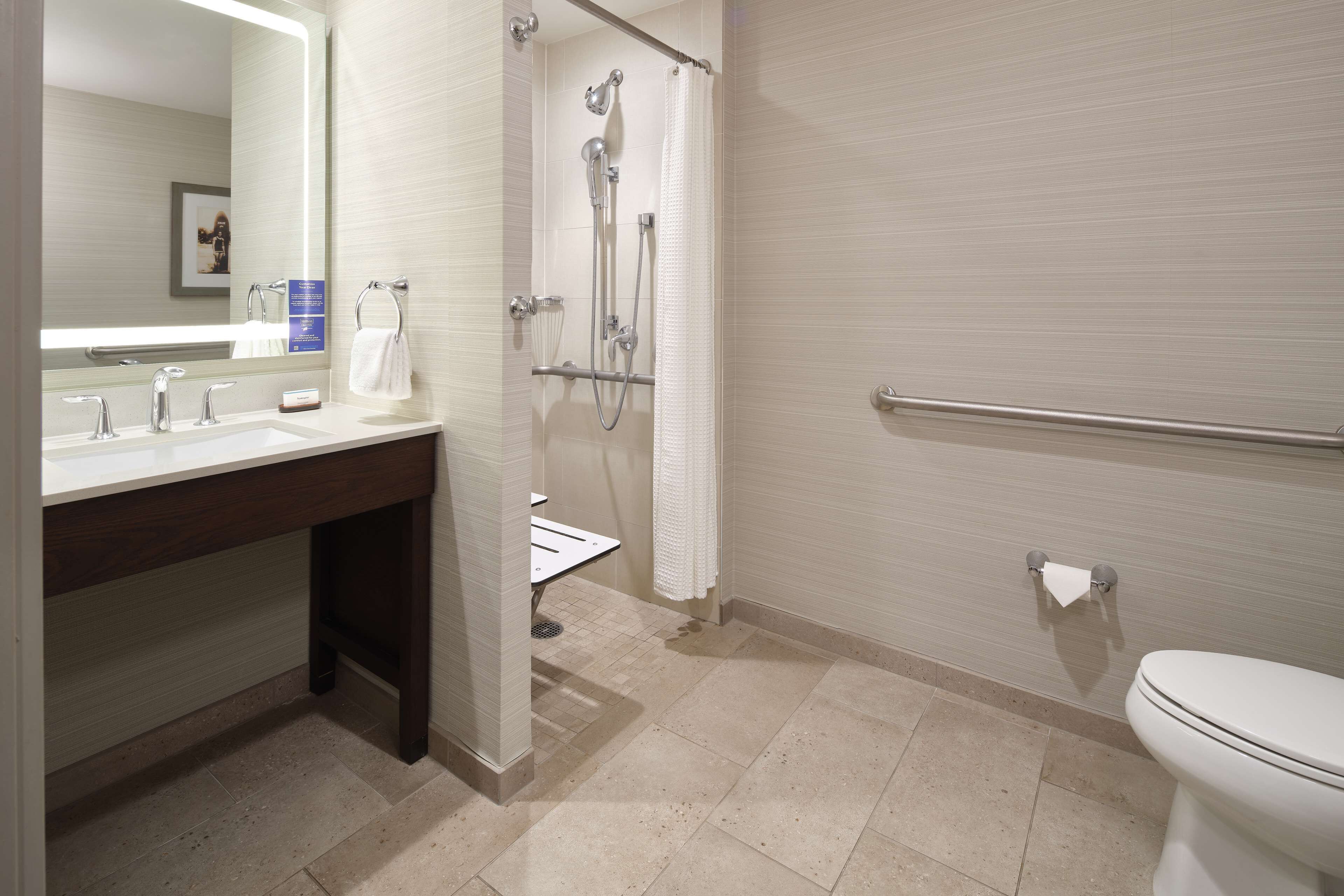 A modern bathroom with a sink, mirror, shower, and toilet.