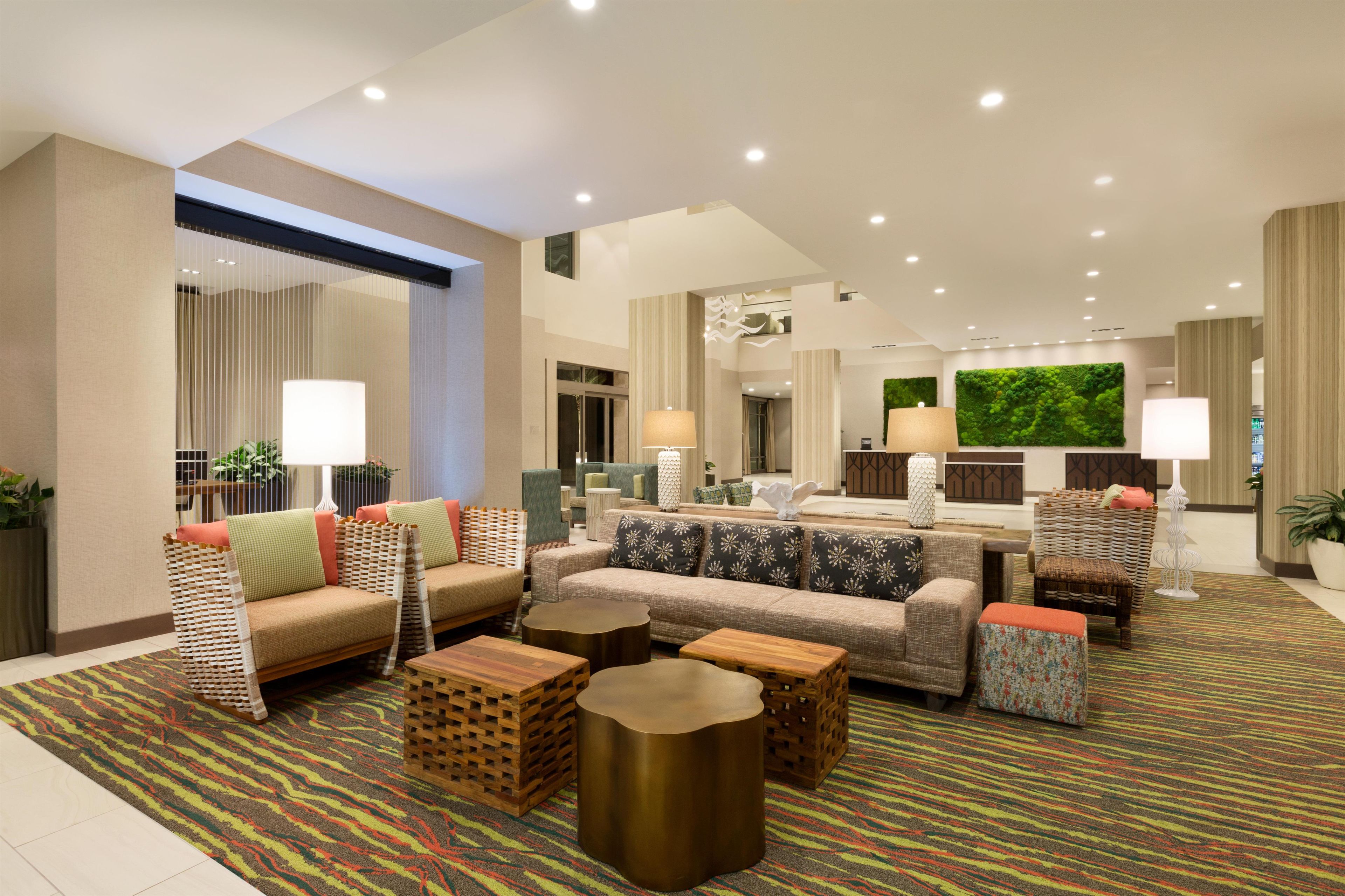 A spacious lobby with multiple seating areas, including sofas and armchairs, and a central coffee table.