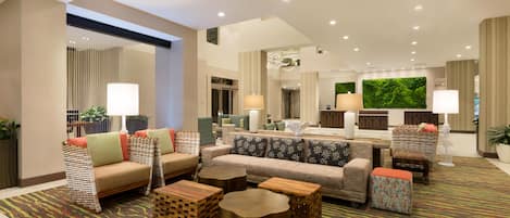 A spacious lobby with multiple seating areas, including sofas and armchairs, and a central coffee table.