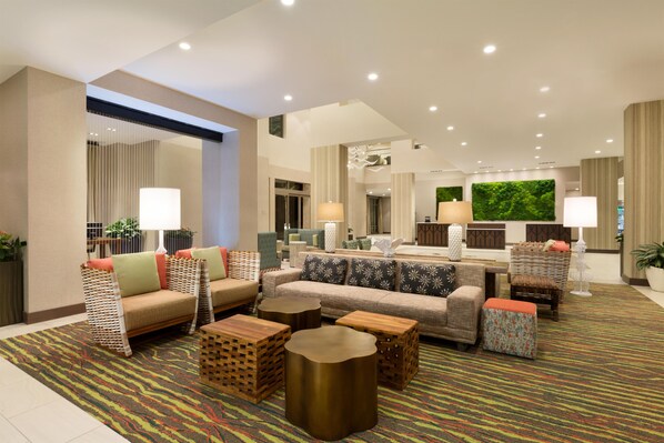 A spacious lobby with multiple seating areas, including sofas and armchairs, and a central coffee table.