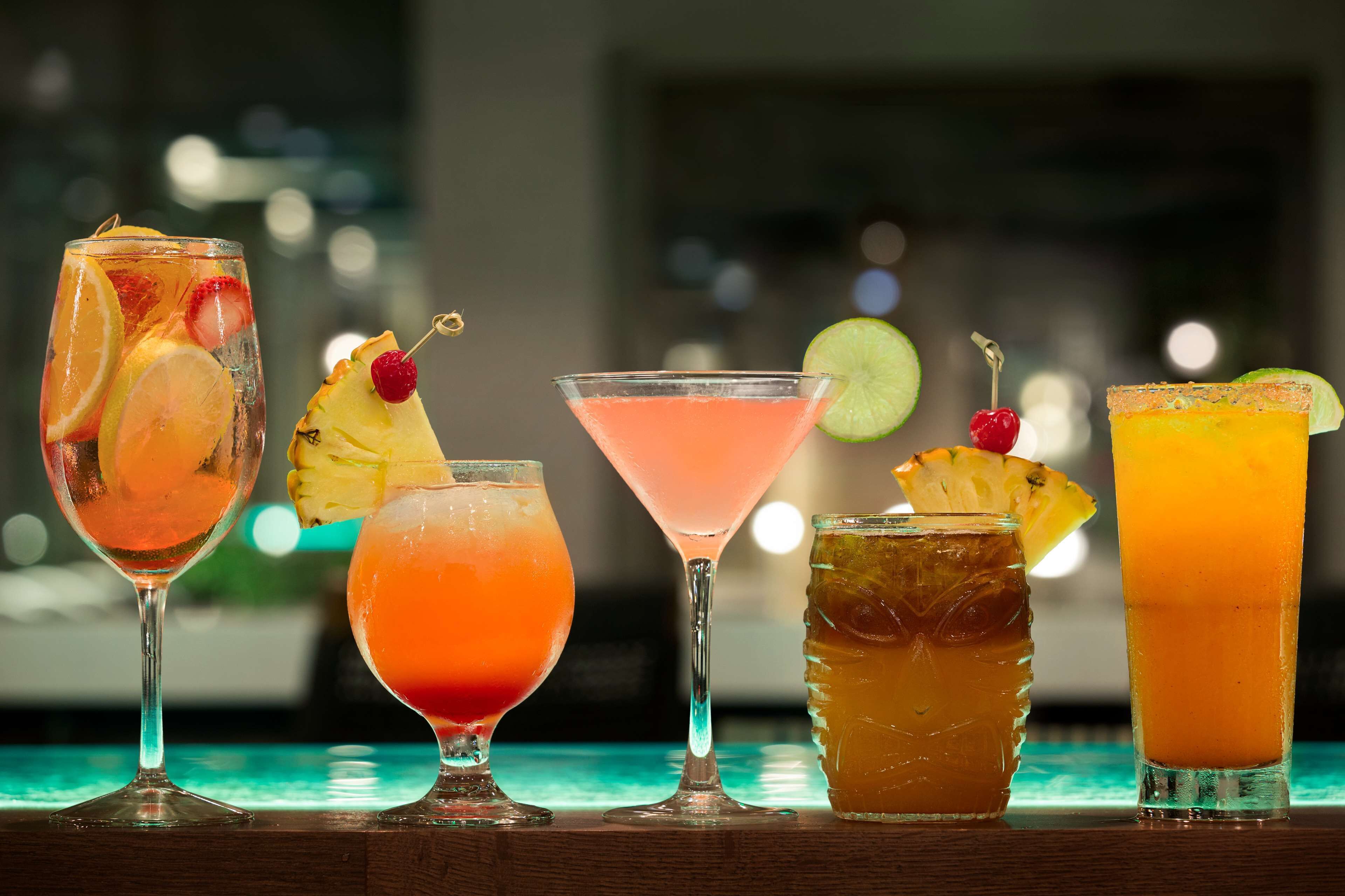 Five different cocktails with garnishes, served in various glassware.