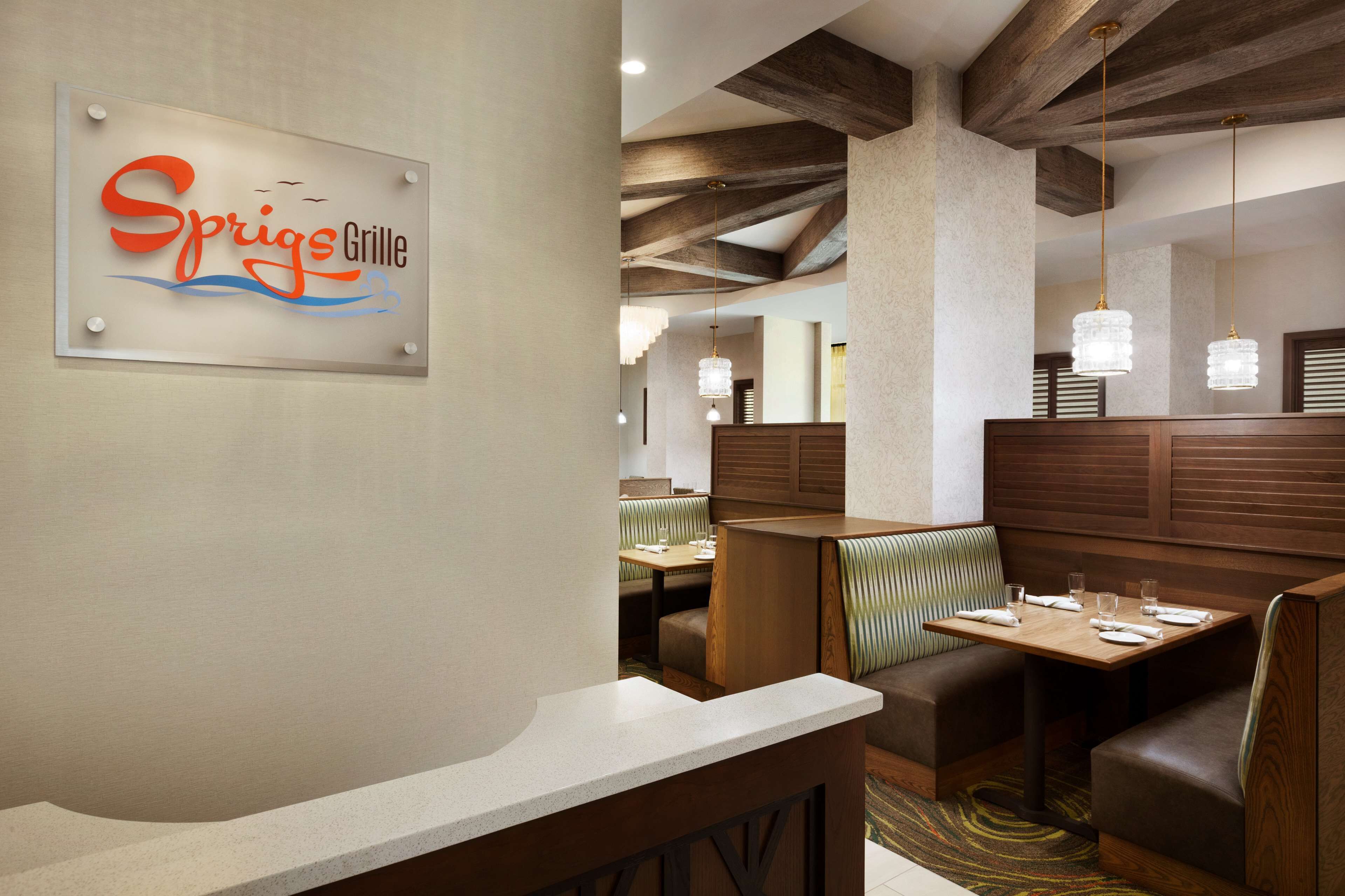 A restaurant interior with booths, tables, and a sign reading "Sprigs Grille".