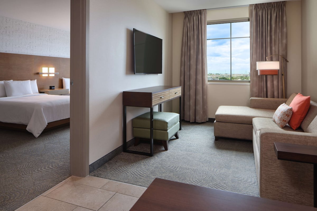 Een hotelkamer met een bed, een slaapbank, een bureau, een televisie en een raam met gordijnen.