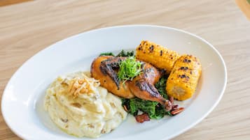 A plate with roasted chicken, corn on the cob, and mashed potatoes.