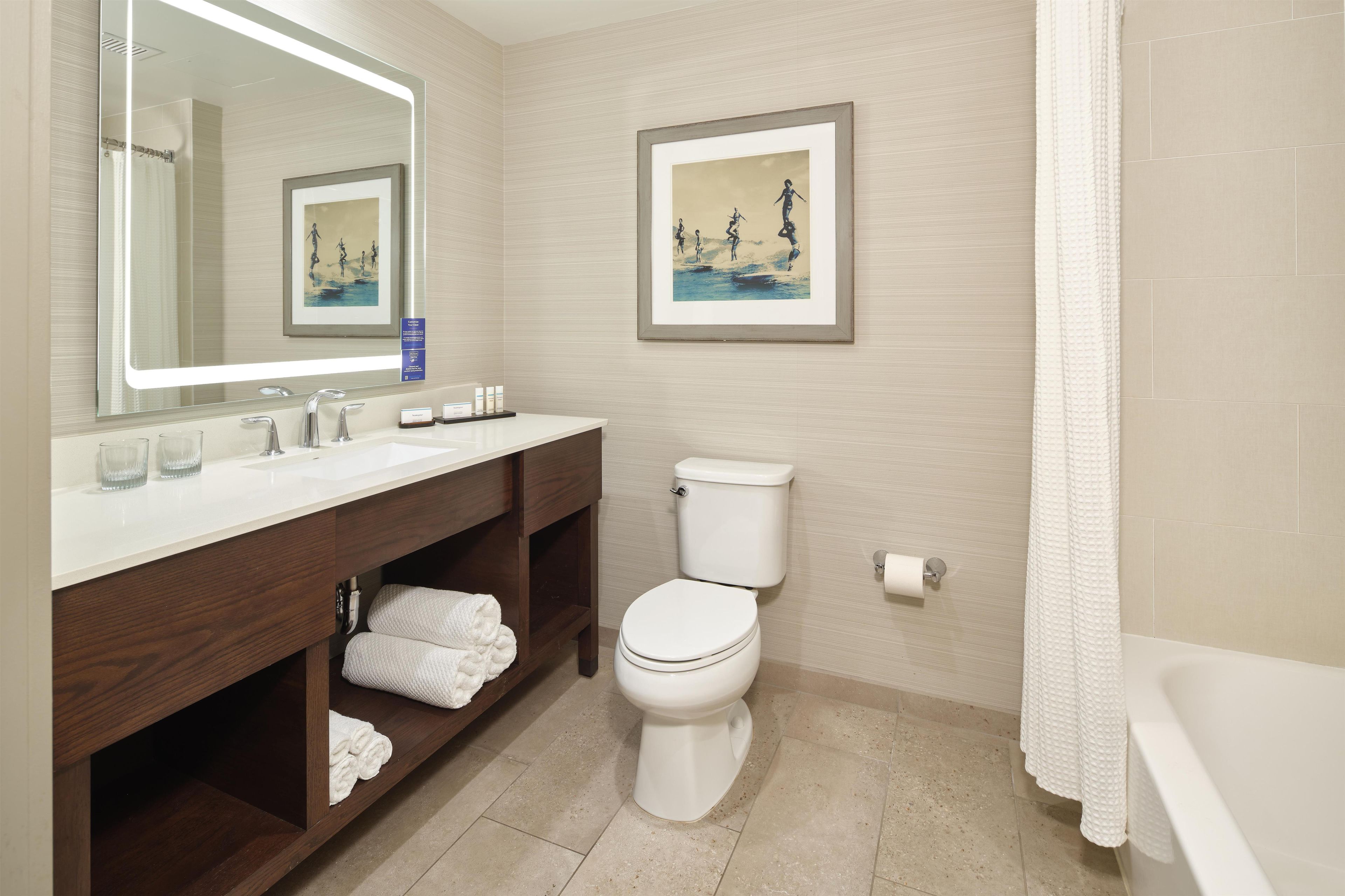 Ein Badezimmer mit Toilette, Waschbecken mit Spiegel und einem gerahmten Bild an der Wand.