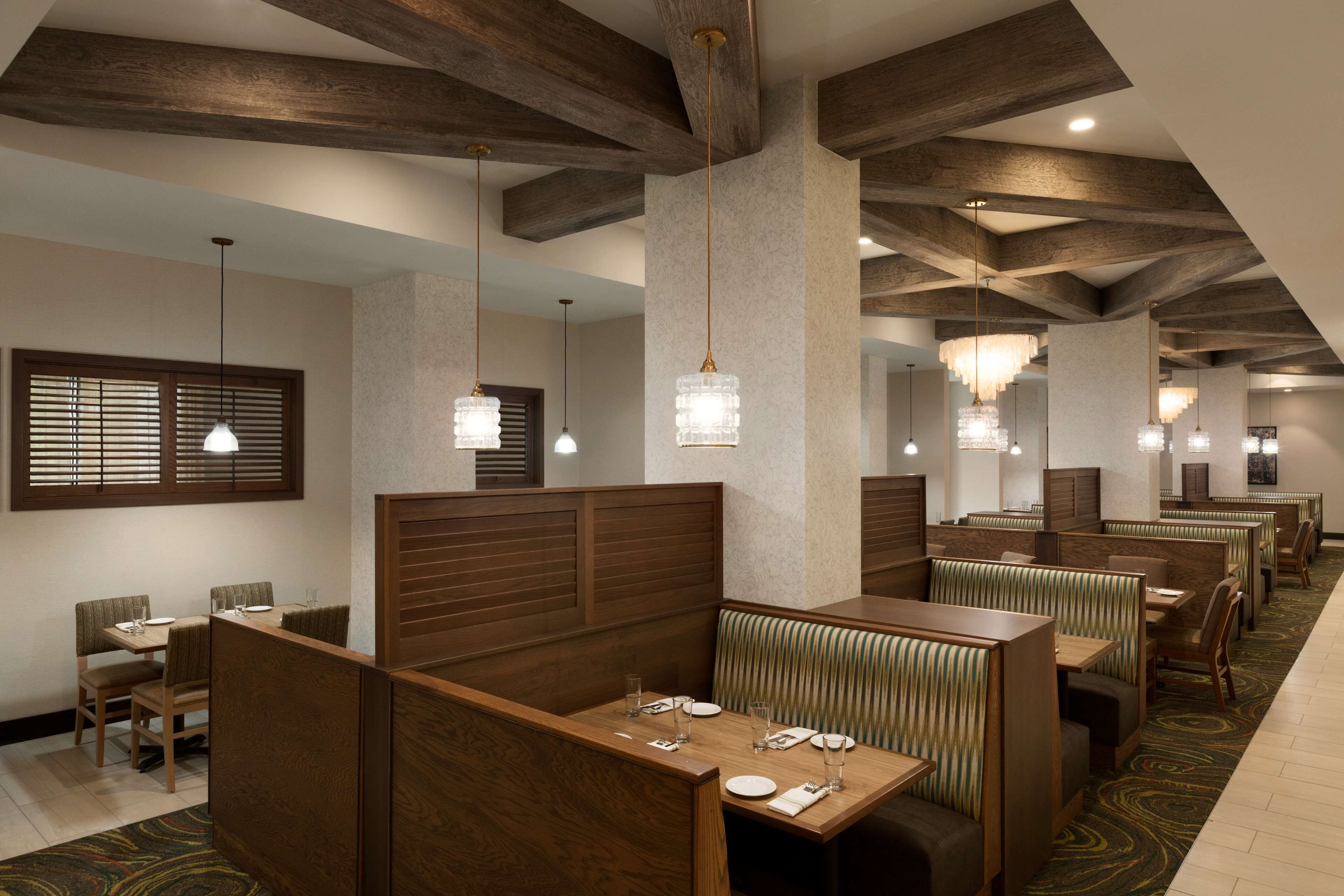 Un restaurante con cabinas de madera, techos altos con vigas a la vista e iluminación colgante.