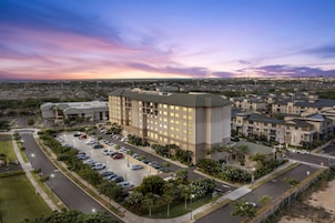 A large hotel with multiple floors, a parking lot, and a view of the surrounding area.