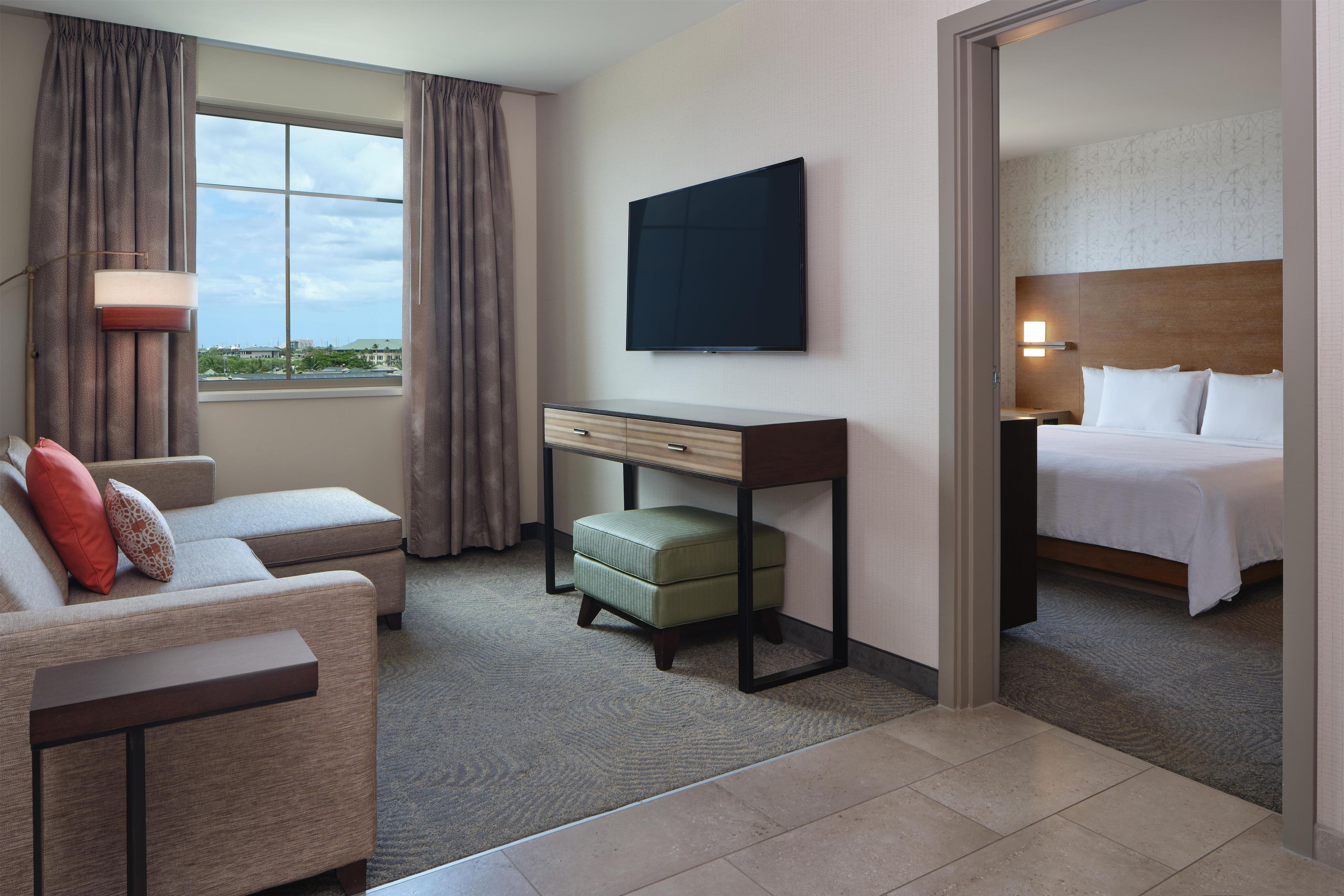 Quarto de hotel com cama, escrivaninha, cadeira e vista para o exterior.