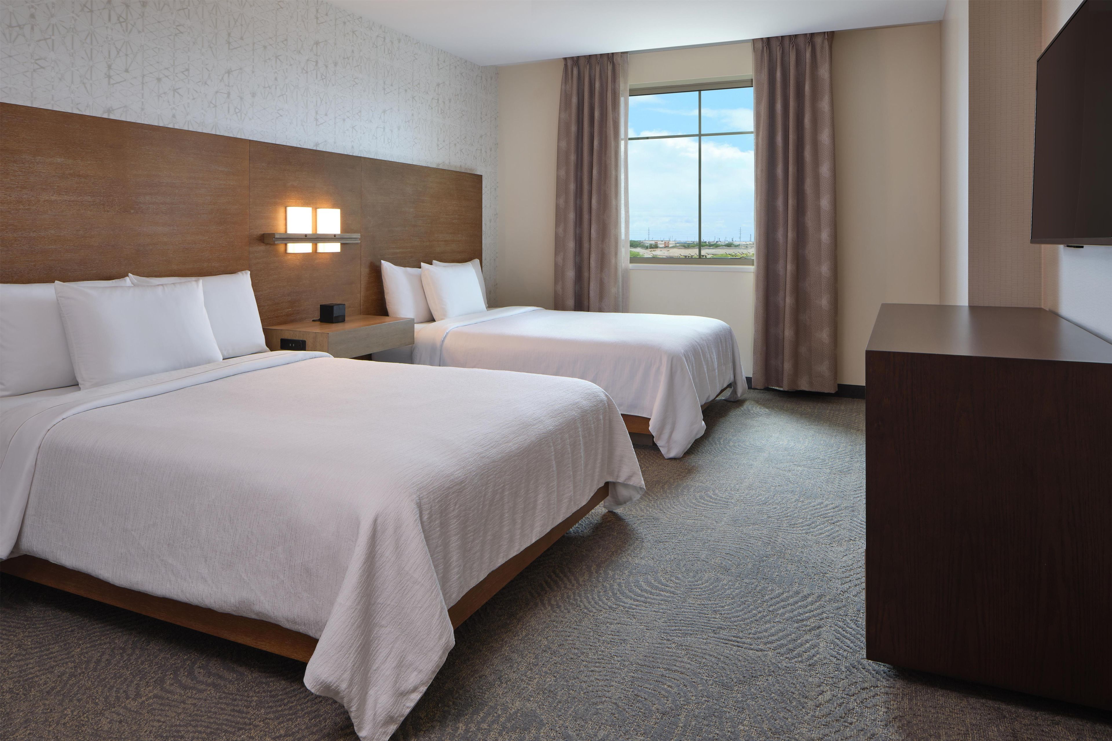 A hotel room with two beds, a desk, and a television.