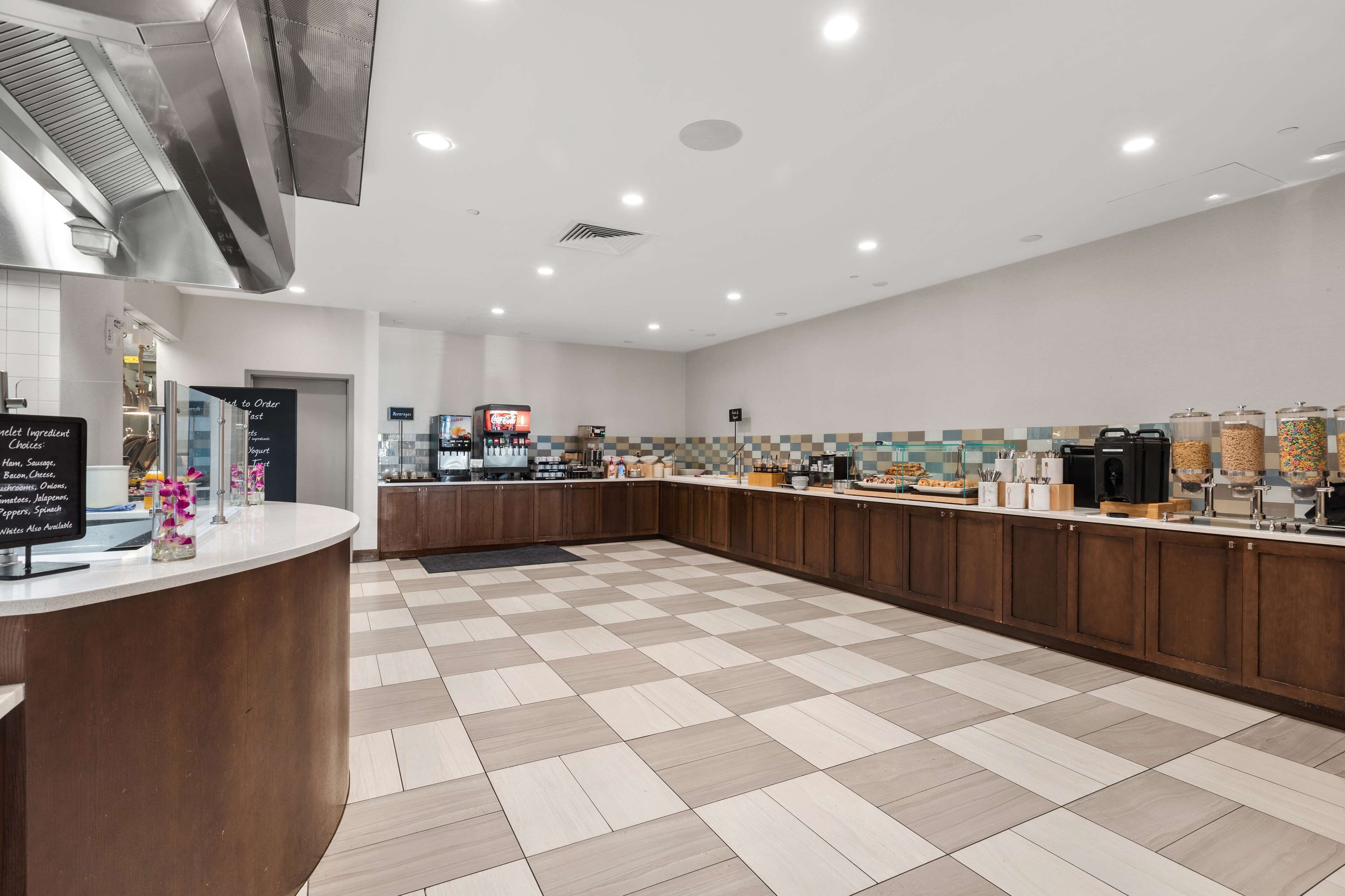 Una cocina moderna con piso a cuadros, una estación de café y un cartel que indica ingredientes disponibles.