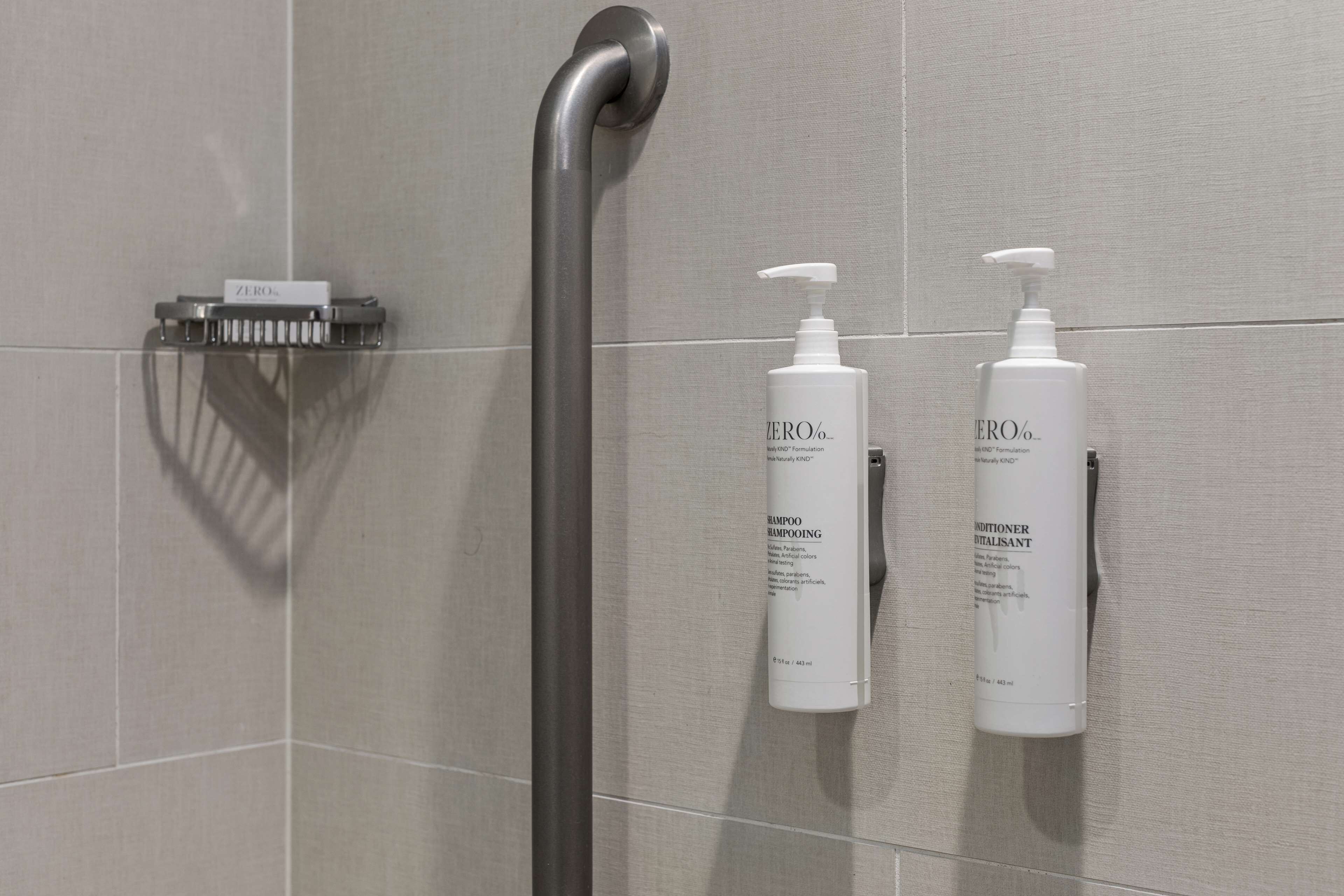Ein Badezimmer mit Dusche, einem Handtrockner sowie zwei Flaschen Shampoo und Conditioner.