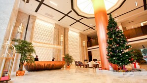 A spacious lobby with a reception desk, a large Christmas tree, and a unique orange planter. - Lamtin Longwin Hotel Wuhan (Wuhan)