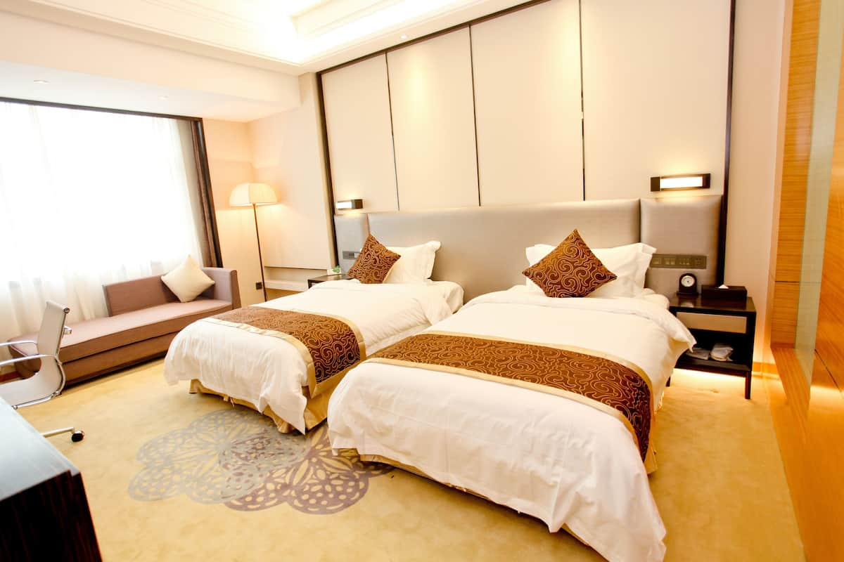 Une chambre d’hôtel avec deux lits, un canapé, un bureau et une lampe.