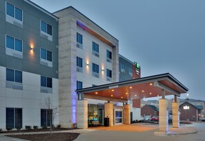 Um hotel com entrada coberta, várias janelas e a placa do Holiday Inn Express & Suites.