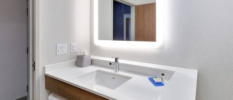Un baño con un lavabo blanco, un espejo y un perchero para toallas.