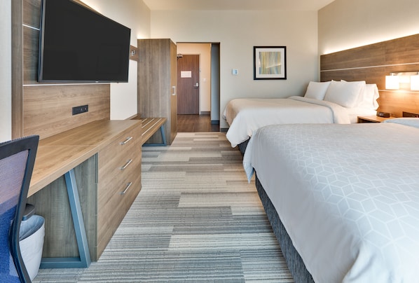 A hotel room with a flat-screen TV, a desk with drawers, two beds with white bedding, and a patterned carpet. - Holiday Inn Express & Suites Plano East - Richardson by IHG (Plano)