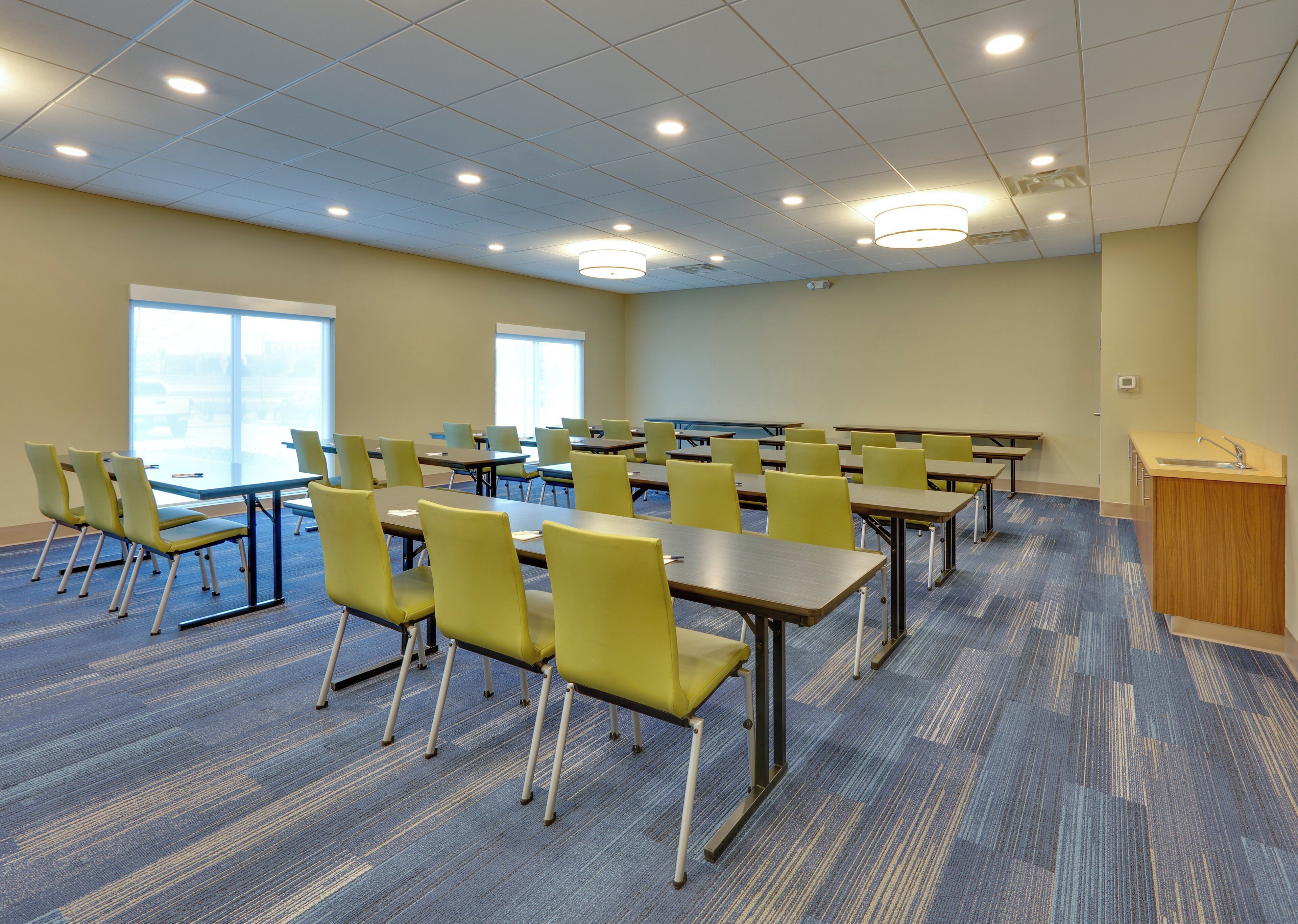 A conference room with tables and chairs, a podium, and a view through large windows.