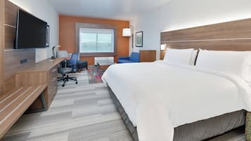 Habitación de hotel con una cama grande, un escritorio, un televisor de pantalla plana, una silla, una ventana y un cabecero.